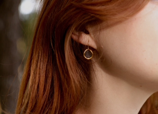 Minimal gold and porcelain earrings worn by model.